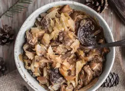 Miska pełna bigosu z kiszonej kapusty i mięsa, widok z góry.