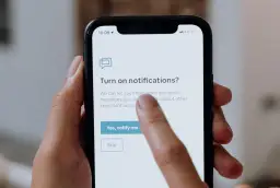 Palec dotyka ekranu telefonu, wybierając opcję "Yes, notify me" (Tak, powiadom mnie) na ekranie z pytaniem o włączenie powiadomień po polsku.