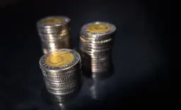 Stosy monet pięciozłotowych na ciemnym tle. Zastanawiasz się, jakie odszkodowanie za przekopanie działki?