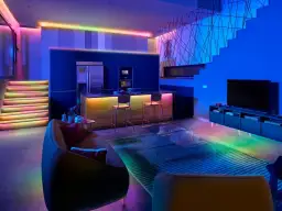 Nowoczesne wnętrze z kolorowymi ledami na suficie bez podwieszanego sufitu, oświetlającymi schody, kuchnię i salon.