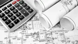 Kalkulator i plany budowlane leżą obok siebie, sugerując obliczenia dotyczące tego, ile kosztuje przyłącze elektryczne.