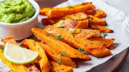 Pieczone frytki z batatów z zielonym dipem i limonką.