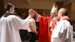 Biskup udziela sakramentu bierzmowania dorosłemu. Warto wiedzieć, ile kosztuje bierzmowanie dla dorosłych, choć cena jest symboliczna.