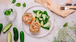 Bagiel z łososiem i jajkiem, sałatka z ogórka i szpinaku, woda z miętą.