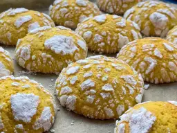 Popękane ciasteczka cytrynowe, posypane cukrem pudrem, wyglądają jak małe, słodkie śnieżki.