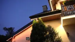 Eleganckie oświetlenie w podbitce domu, rozmieszczone co kilka metrów, tworzy ciepłą atmosferę wieczorem.