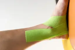 Taping na stopę koślawą u dziecka, zielona taśma kinezjotapingowa stabilizuje staw skokowy.