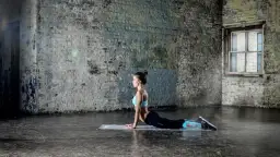 Kobieta ćwicząca pilates w pozycji kobry na macie w industrialnym wnętrzu.