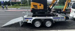 Żółta minikoparka SY18C na przyczepie. Zastanawiasz się, ile waży minikoparka? Ta jest gotowa do transportu.