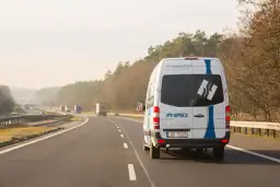Biały bus AR-SPEED jedzie autostradą. Zastanawiasz się, ile kosztuje bus do Niemiec? Sprawdź na ar-speed.pl.
