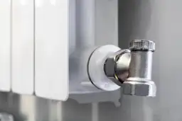 Metalowy zawór grzejnikowy, pokazujący, jak zakręcić grzejnik bez pokrętła, używając klucza.
