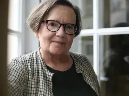 Portret starszej kobiety w okularach, w kratowanej koszuli.