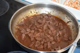 Kawałki wieprzowiny duszą się w sosie, co jest kluczowe, jak zmiękczyć twarde mięso wieprzowe na gulasz naturalnymi metodami.