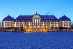 Grand Hotel w Sopocie, jeden z najpiękniejszych hoteli w Polsce, lśni nocą nad piaszczystą plażą.