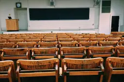 Puste drewniane ławki w sali wykładowej, jakby czekające na studentów w futurystycznym francuskim uniwersytecie.