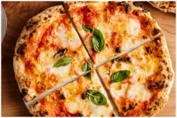 Margherita z puszystym ciastem i prawdziwym sosem do pizzy, ozdobiona świeżą bazylią.