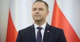 Mężczyzna w garniturze przed polską flagą. Czy to symbol ukrytych kosztów utrzymania Kancelarii Prezydenta RP w ostatnim roku kadencji?