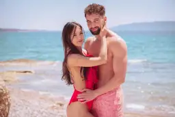 Para zakochanych na plaży, w objęciach, z morzem w tle. Ich spojrzenia mówią wszystko, bo love never lies.