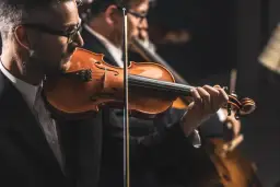 Skrzypek grający utwór Wolfganga Amadeusa Mozarta. W tle inni muzycy orkiestry.