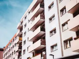 Jasny budynek z wieloma balkonami, idealny dla kogoś, kto szuka mieszkania na parterze.