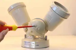 Regulacja czujnik ruchu 3 pokrętła. Ręka z wkrętakiem dostosowuje ustawienia czujnika ruchu.