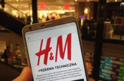 Telefon z logo H&M na ekranie, w tle sklep.