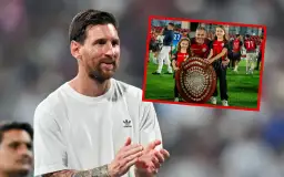 Lionel Messi, najbardziej utytułowany piłkarz w historii, uśmiecha się, podczas gdy w tle widać jego drużynę świętującą z pucharem.