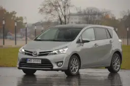 Srebrny minivan Toyota Verso zaparkowany na mokrej nawierzchni w deszczowy dzień.