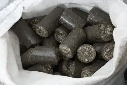 Worek pełen walcowatych brykietów, idealnych jako ekologiczne paliwo do pieca.