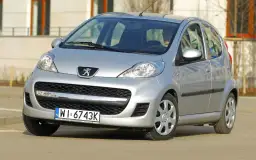 Srebrny Peugeot 107 z przodu, widoczny kierowca.