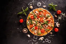 Pyszna pizza z pomidorami i bazylią, pokrojona na kawałki. Zastanawiasz się, ile kcal ma kawałek pizzy?