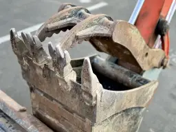 Zębata łyżka krusząca do koparki, gotowa do rozbijania skał i betonu.