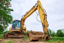 Żółta koparka gąsienicowa na placu budowy. Zastanawiasz się, jaki olej hydrauliczny do koparki będzie najlepszy?