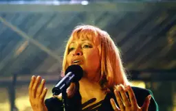 Zdzisława Sośnicka śpiewa przy mikrofonie, gestykulując rękami.