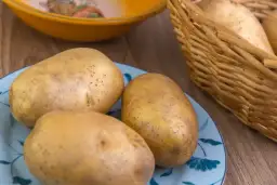 Ziemniaki na talerzu i w koszyku. Zastanawiasz się, co sadzić po ziemniakach? Wybierz rośliny strączkowe lub kapustne.