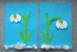 Dwie prace plastyczne wiosenne: białe przebiśniegi z zielonymi łodygami na niebieskim tle, ozdobione kłębkami waty u podstawy.