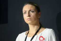 Posłanka Kinga Gajewska z zamyśloną miną, w białej bluzce z czerwonym sercem.
