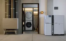 Nowoczesny kocioł co z podajnikiem 15 kW marki DEFRO, obok pralki i suszarki w pralni.