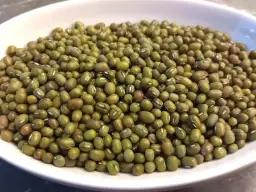 Misternie ułożona fasolka mung w białej misce. Czy fasola tuczy? Ta zielona bogactwo białka to świetny dodatek do diety.