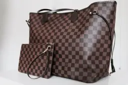Duża torebka Louis Vuitton w kratkę, obok mniejsza kosmetyczka. Klasyczny wzór Damier Ebene.