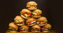Stos pysznych domowych hamburgerów z sezamem, serem, sałatą i warzywami.