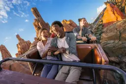 Radość na rollercoasterze w europejskim Disneylandzie. Grupa przyjaciół krzyczy z ekscytacji, przeżywając przygodę wśród skalistych krajobrazów.