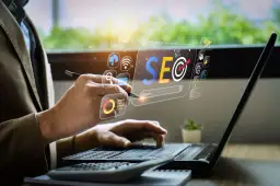 Osoba pracuje przy laptopie, analizując dane SEO. Wirtualny interfejs pokazuje ikony związane z marketingiem cyfrowym. To praca content seo manager co to jest.