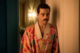 Freddie Mercury w barwnym szlafroku, jakby zrodzony z **bohemian rhapsody**, opiera się o drzwi.