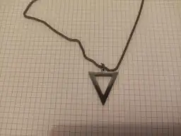 Czarny naszyjnik z wisiorkiem w kształcie pustego trójkąta, który może symbolizować żywioł ziemi.