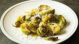 Pyszna sałatka z brukselką, pieczona z parmezanem i oliwą, podana na białym talerzu.