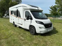 Biały kamper Burstner Lyseo Harmony Line stoi na zielonej trawie.