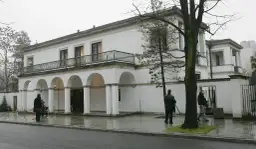 Biała willa z arkadami, gdzie mieszka Donald Tusk. Na zewnątrz widać kilka osób i drzewa.