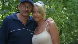 Mężczyzna w okularach i czapce obejmuje kobietę w bluzce na ramiączkach.