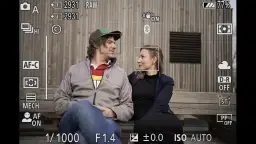 Widok z wizjera aparatu Nikon, pokazujący parę. Na ekranie widać ustawienia AF-C i AF ON, co pomaga zrozumieć, jak ustawić ostrość w aparacie Nikon.